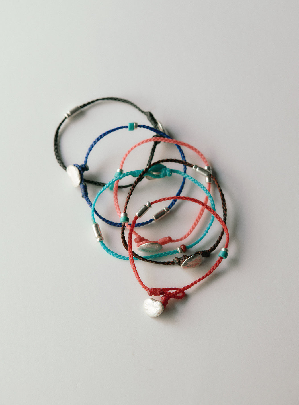 Waxed cord bracelet with irregular silver ornaments and tube beads
